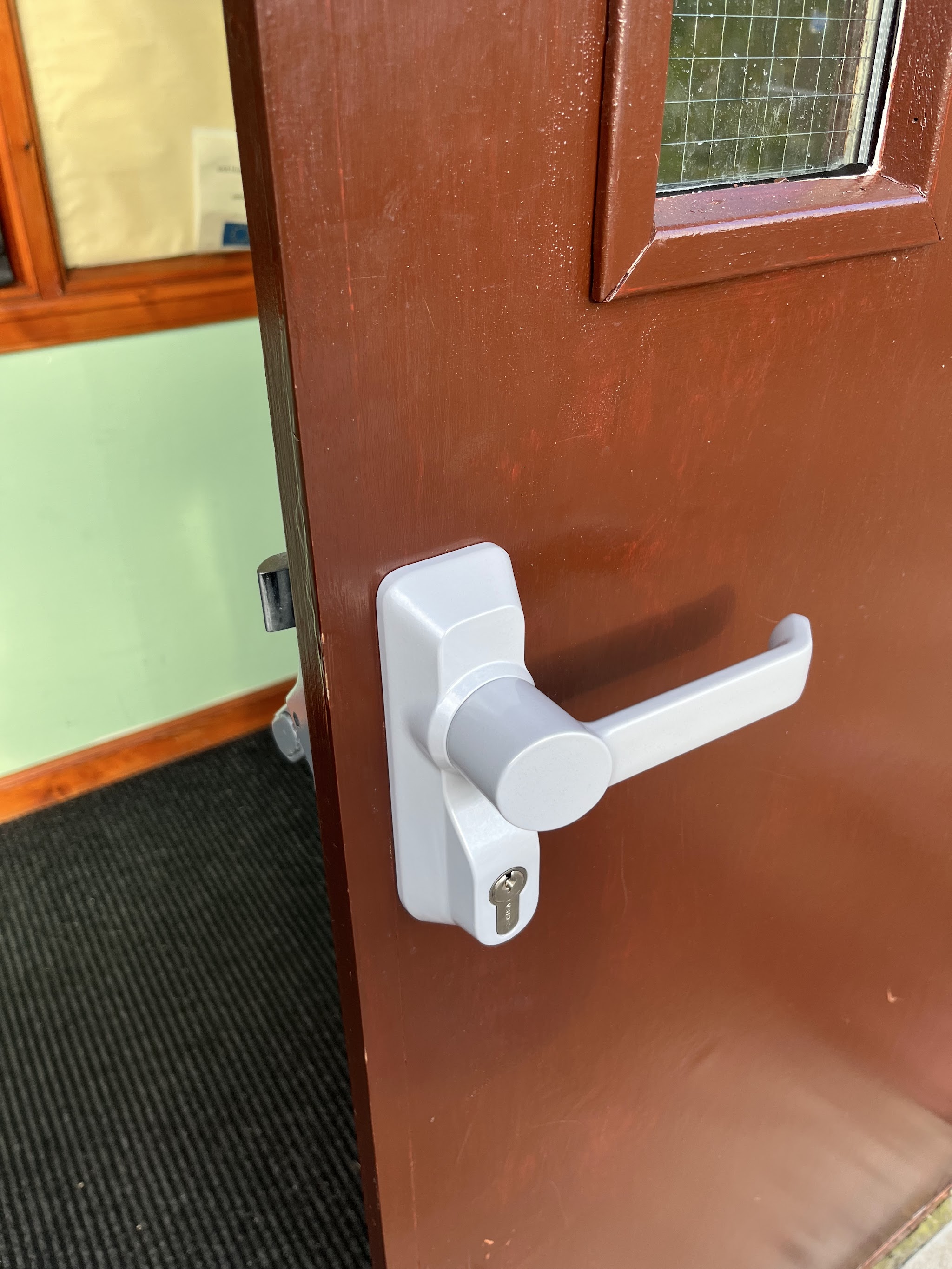 White lever handle and cylinder lock on a red door