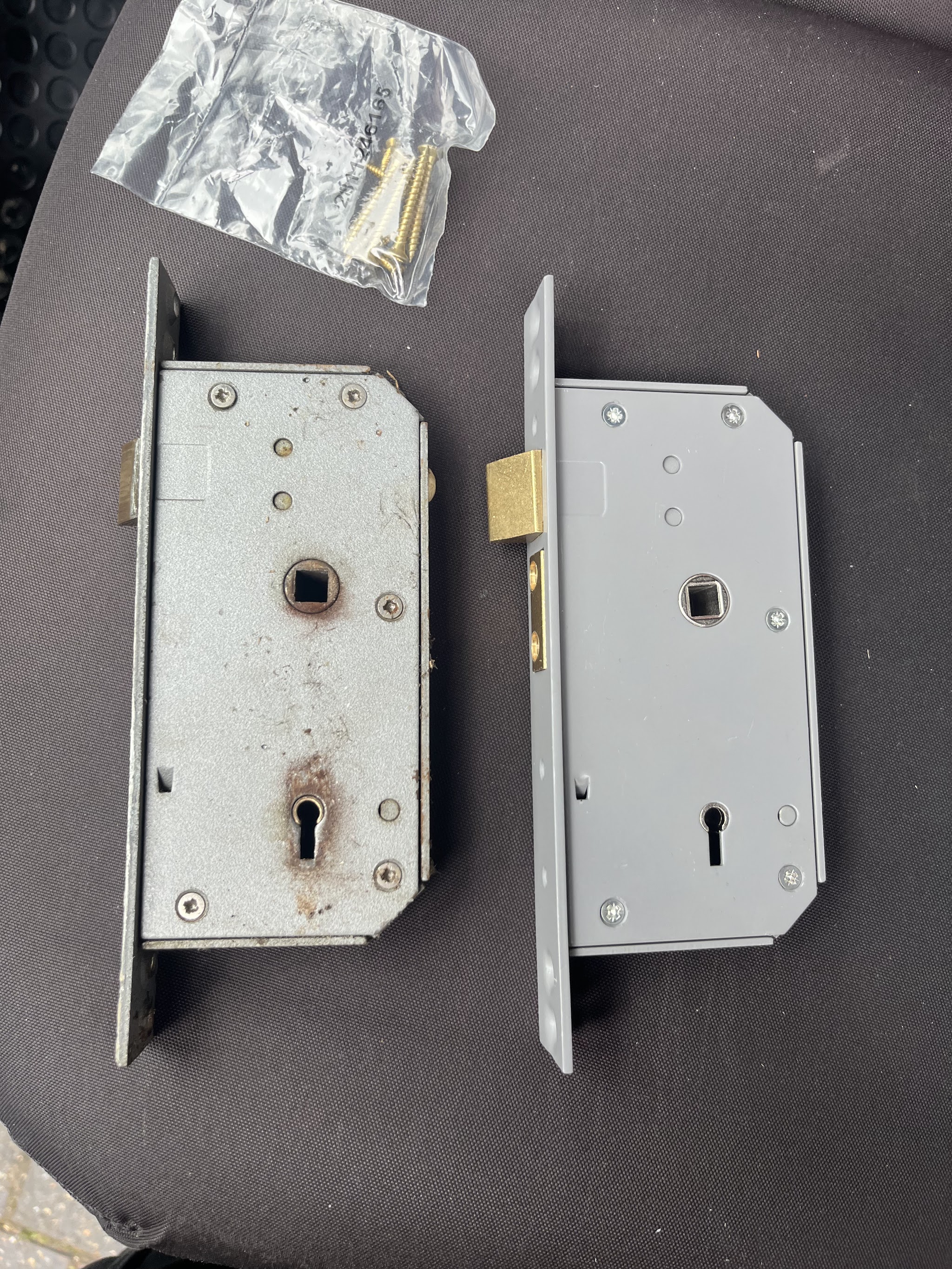 An old rusted mortice sashlock laid beside the new sashlock that replaced it